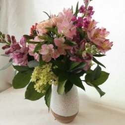 Pink and purple flower arrangement in a white vase