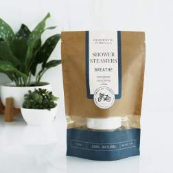 Package of shower steamers beside two potted plants