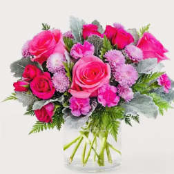 Pink roses and lavender pom-pom flowers in a clear glass vase