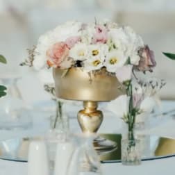 Pastel floral centerpiece in a gold vase on a table