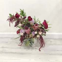 Mixed pink and burgundy floral arrangement in a white vase