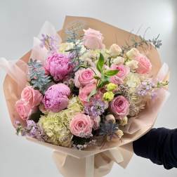 Hand-tied bouquet of pink roses, peonies, and hydrangeas in blush wrap