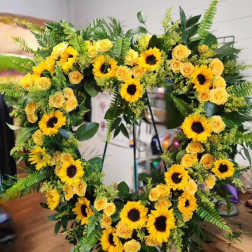 Large floral wreath with yellow sunflowers and roses on a stand