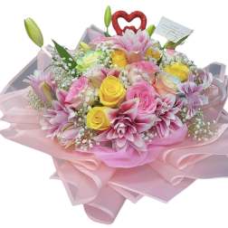 Pink and yellow bouquet with roses and lilies wrapped in pink paper