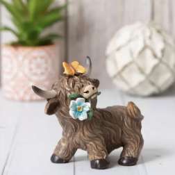 Small decorative cow figurine with flowers on its head and neck