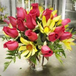 Bouquet of red roses and yellow daisies in a clear vase