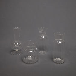 Set of four clear ribbed glass bud vases on a gray background