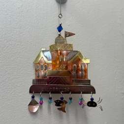 Metal wall hanging shaped like a house with dangling beads and charms