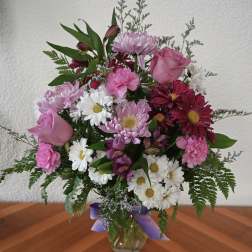 Mixed pink and white bouquet in a glass vase with a purple ribbon