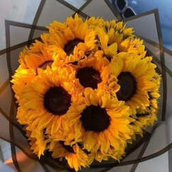 Bouquet of bright yellow sunflowers wrapped in dark paper