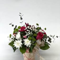 Pink and white flower arrangement in a decorated paper pot