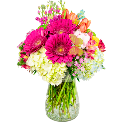 Bright mixed bouquet with pink gerbera daisies and hydrangeas in a glass vase