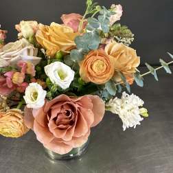 Mixed bouquet of peach, white, and yellow flowers in a glass vase
