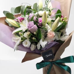 Bouquet of white lilies and pastel roses wrapped in brown paper