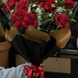 Bouquet of red roses wrapped in black and gold paper with a red ribbon