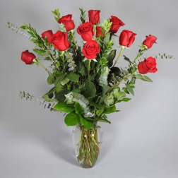 Tall arrangement of long-stemmed red roses in a clear glass vase