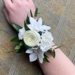 White wrist corsage with layered blooms on a person’s arm