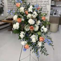 Standing floral spray with white and peach roses and blue accents