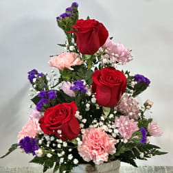 Red roses and pink carnations in a white container with heart tags