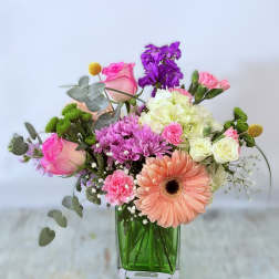Mixed pink and purple flowers in a green glass vase