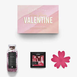 Pink Valentine gift set box with a bath soak bottle, soap, and flower-shaped item