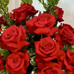 Bouquet of red roses in a glass vase with variegated greenery