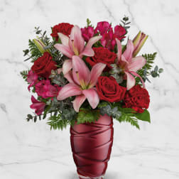Pink lilies and red roses arranged in a red vase