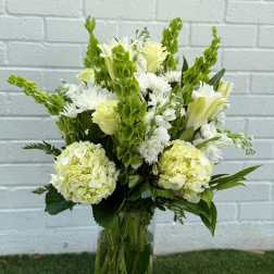 White and pale green floral arrangement in a glass vase
