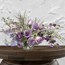 Lavender roses and purple flowers in a clear glass vase