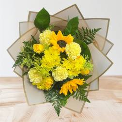 Yellow bouquet with sunflowers, roses, and carnations in tan wrap