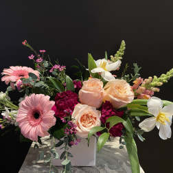 Pink gerbera daisies and peach roses in a white vase