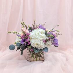 White hydrangea bouquet with pink and purple blooms in a glass vase
