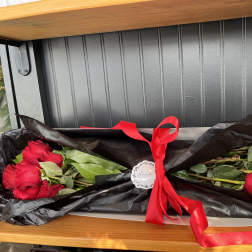 Two bouquets of red roses wrapped in black paper with a red ribbon