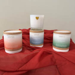 Three scented candles on red fabric, one with a gold heart icon