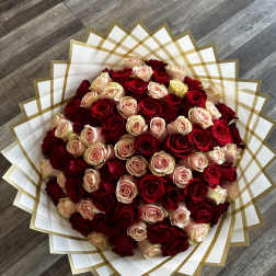 Large bouquet of red and blush roses wrapped in white and gold paper