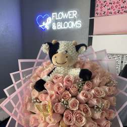 Pink rose bouquet with a plush cow topper and pink wrap
