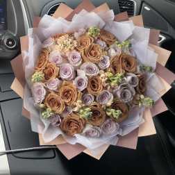 Bouquet of peach and lavender roses wrapped in pale paper