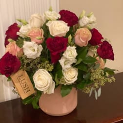 Bouquet of red, white, and blush roses in a pink vase