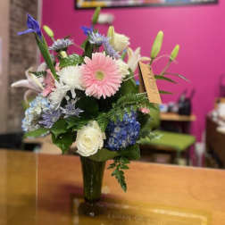 Mixed bouquet of pink, white, and blue flowers in a glass vase