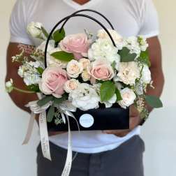 Pink and white roses arranged in a black handled box