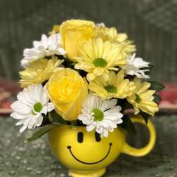 Yellow and white flowers arranged in a smiley-face mug