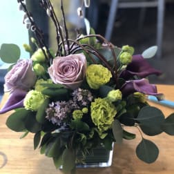 Lavender roses and green carnations in a square glass vase