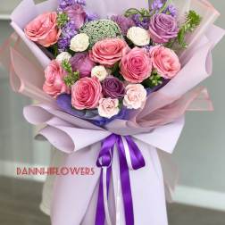 Hand-tied bouquet of pink and purple roses wrapped in lavender paper
