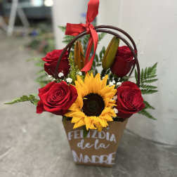 Basket arrangement with red roses and a sunflower, tied with a red ribbon
