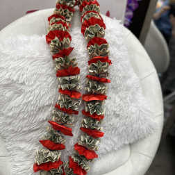 Money lei with red ribbon accents draped over a white chair