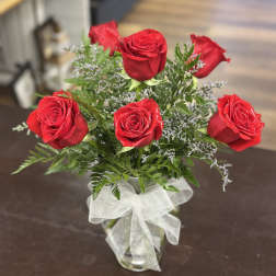Red roses arranged in a clear glass vase with a white ribbon
