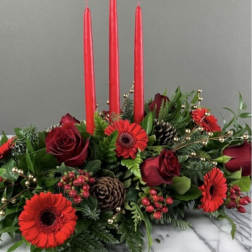Low floral centerpiece with red roses, red gerbera daisies, and tall red candles