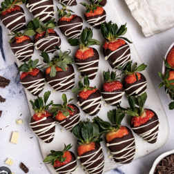 Chocolate-covered strawberries with white drizzle on a tray
