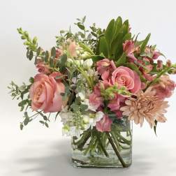 Pink roses and mixed flowers arranged in a clear glass vase