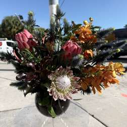 Mixed bouquet of pink and orange flowers in a black vase